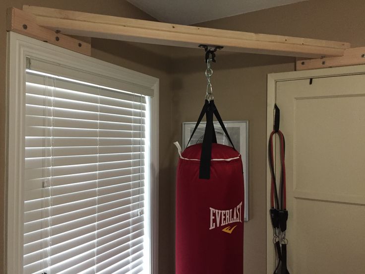 a red boxing bag hanging from the ceiling in a room with white shutters and wooden slats