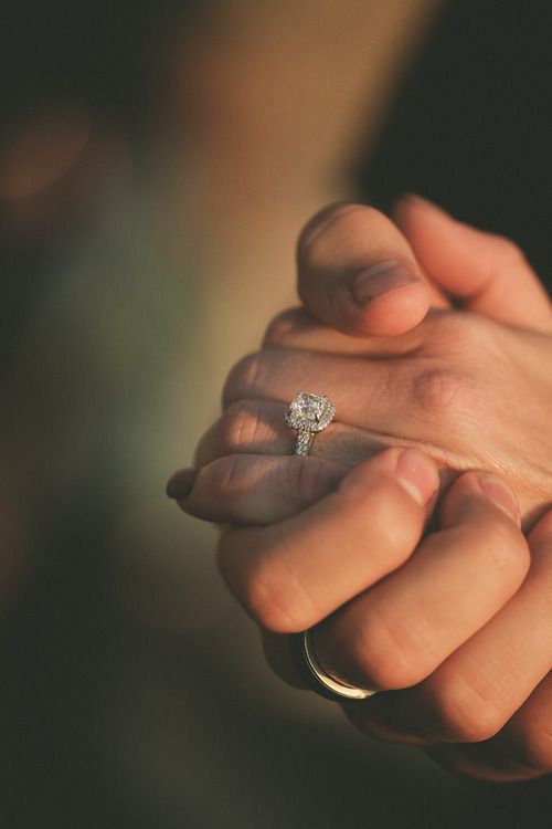 two hands holding each other with a diamond ring on their finger