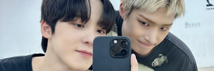 two young men are taking a selfie with their cell phones in front of them