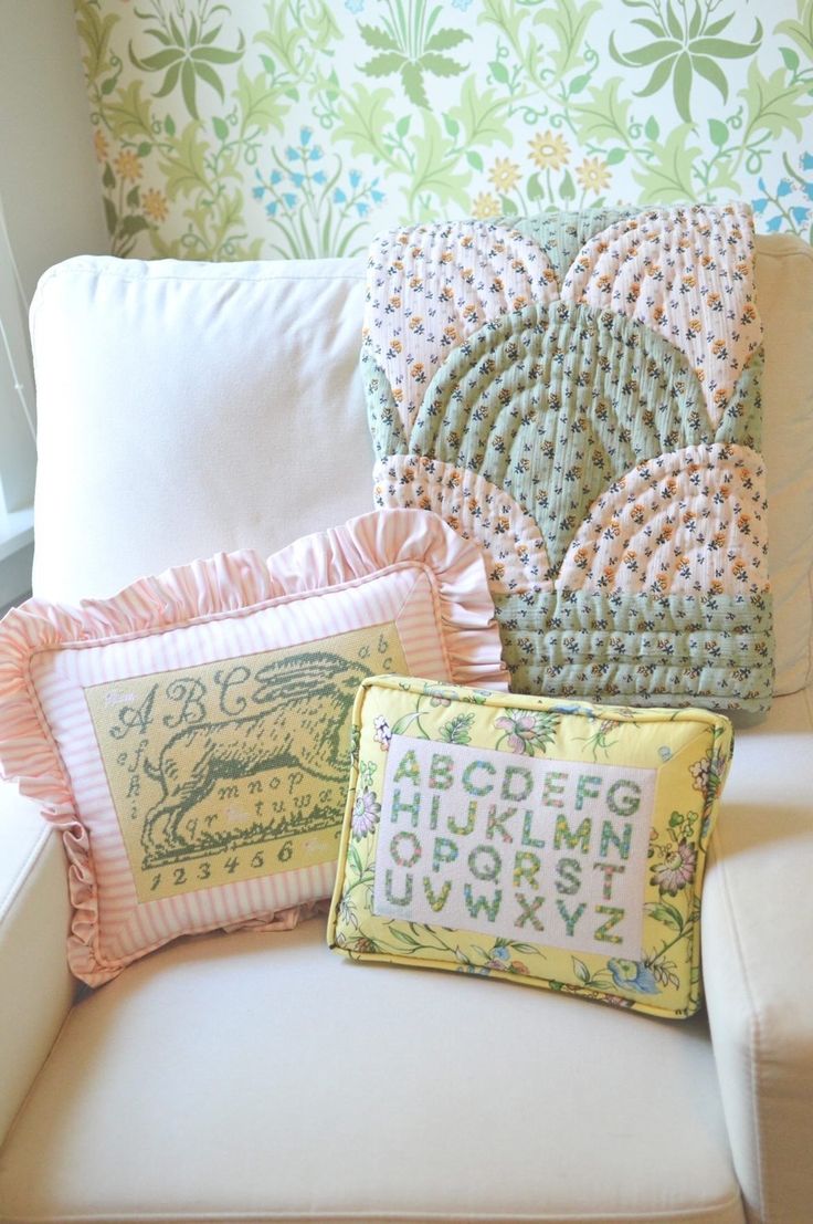 three pillows sitting on top of a white couch