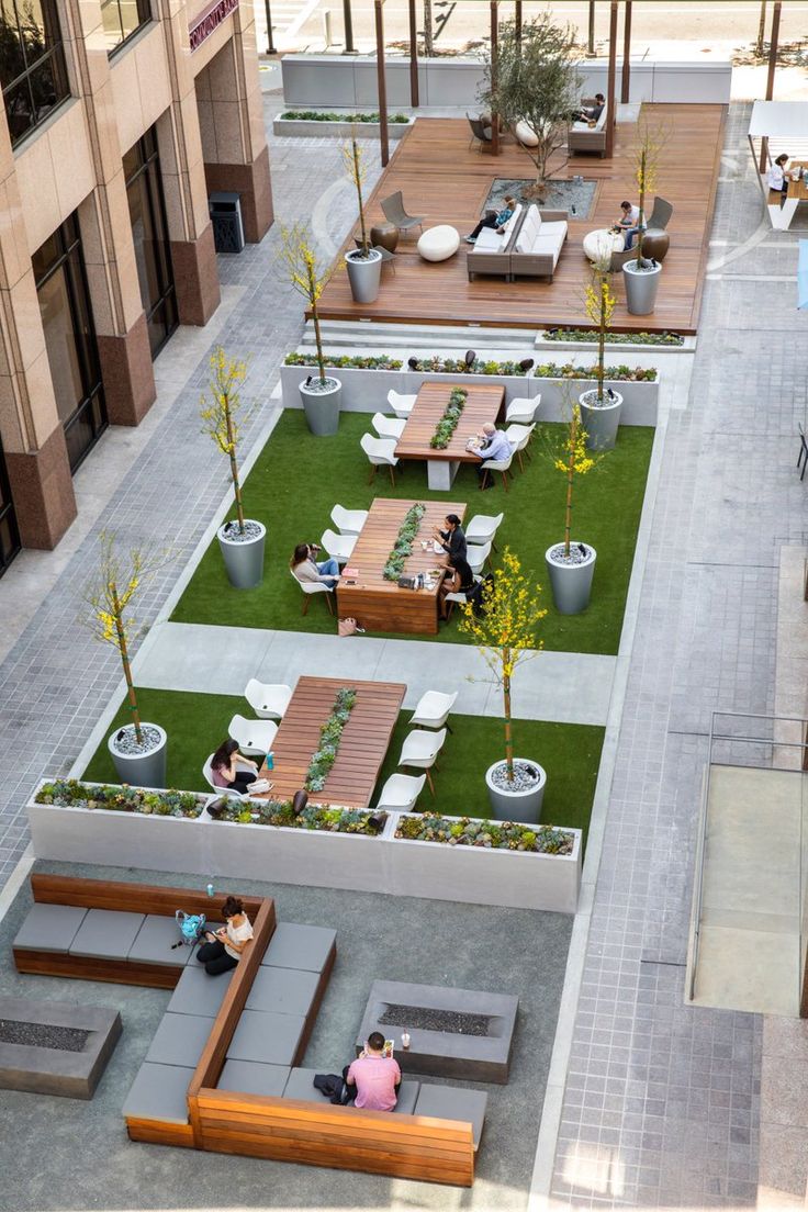 an aerial view of people sitting on lounges and tables in a courtyard area with grass