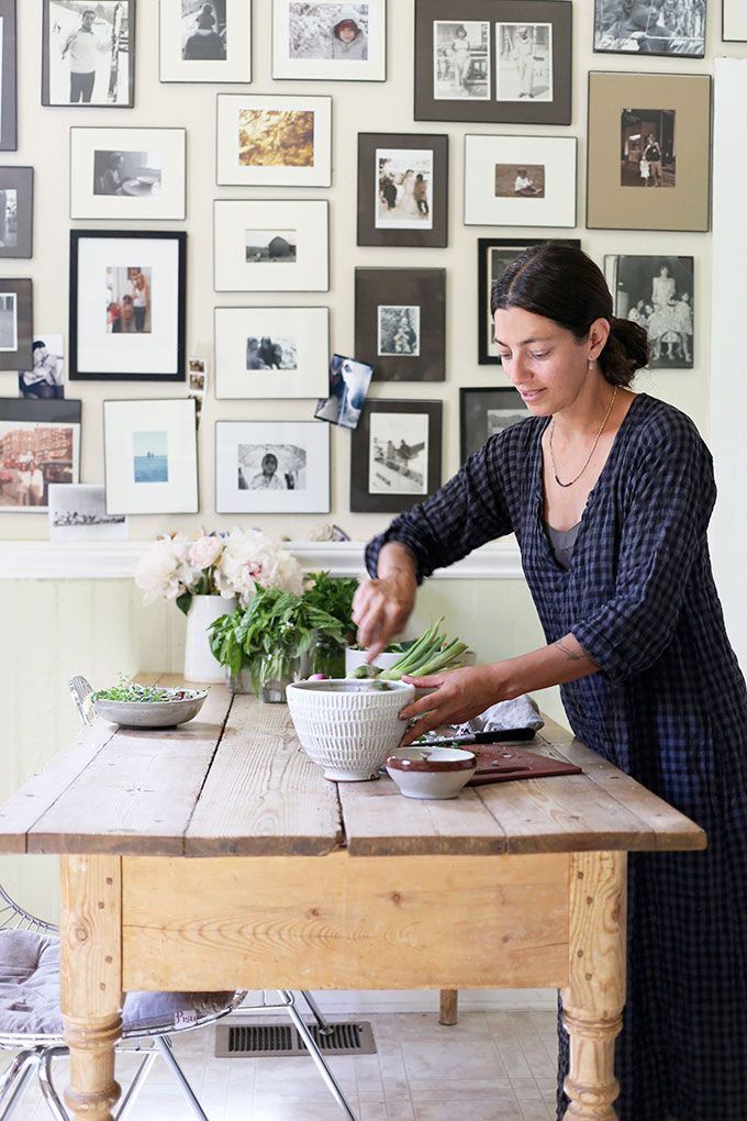 a woman standing in front of a wooden table with a bowl on top of it