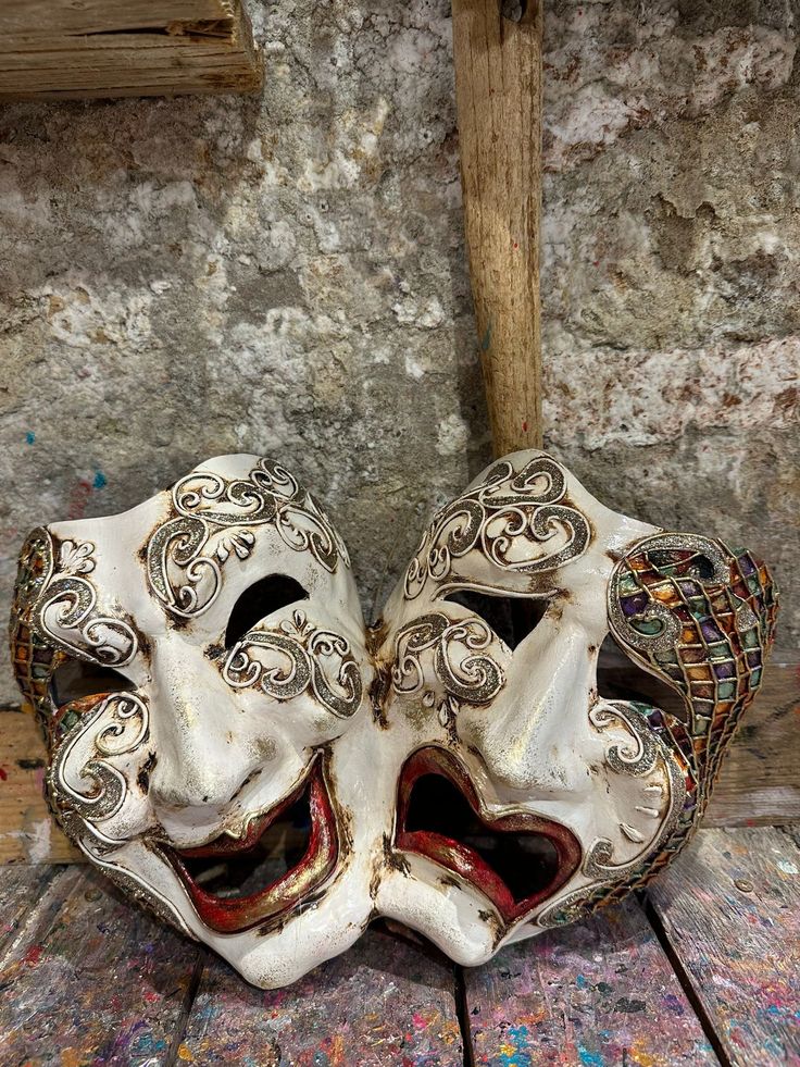 two white masks sitting on top of a wooden floor