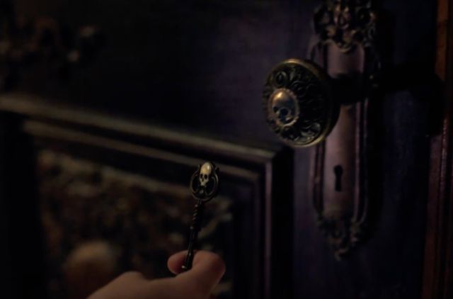 a person is holding a door handle in front of a dark room with ornate doors