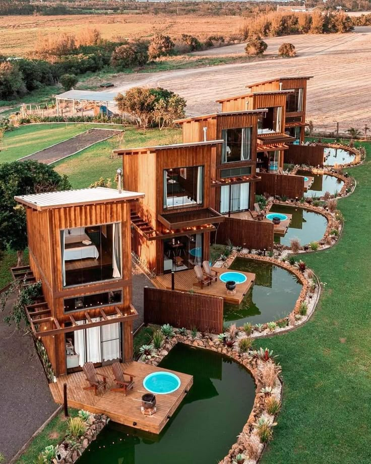 an aerial view of several wooden houses in the middle of a grassy area with small pools