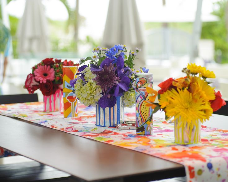 four vases filled with colorful flowers sitting on top of a table covered in cloth