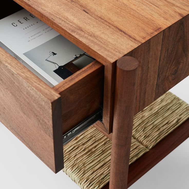 a wooden table with an open drawer and magazine in it's center section, on white background