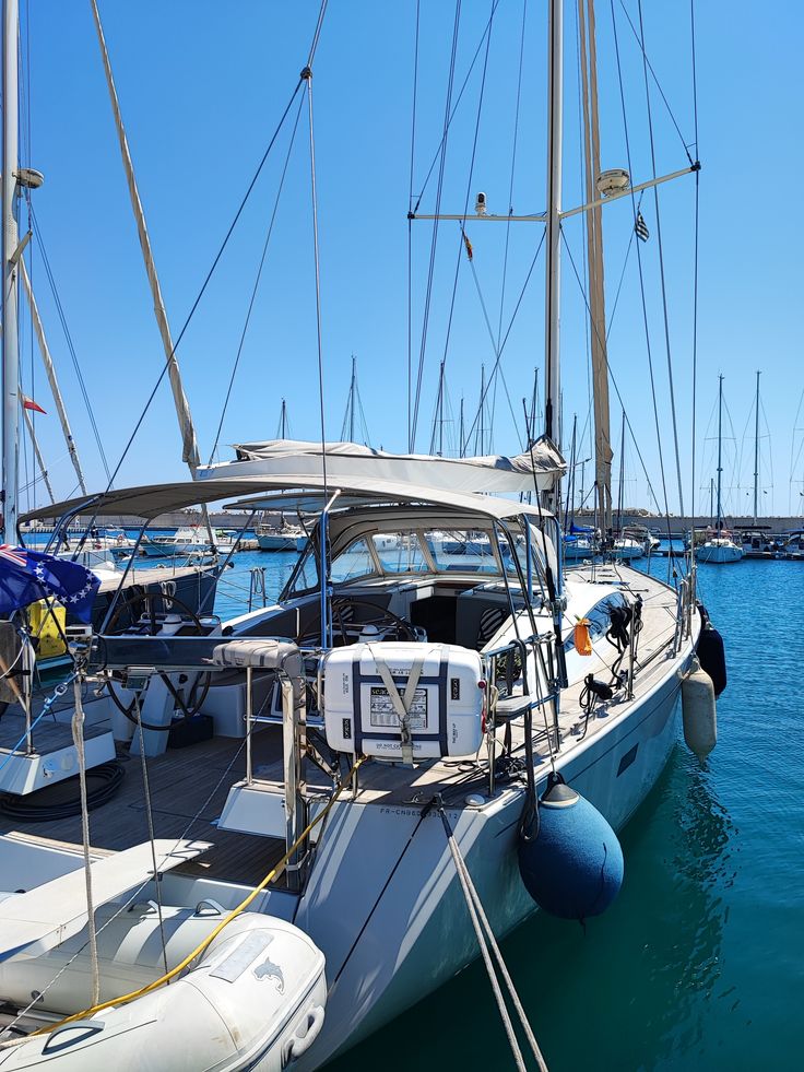 several sailboats are docked in the water near each other on a sunny day with clear blue skies