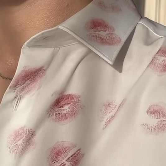 a close up of a woman's shirt with red lipstick prints on the collar