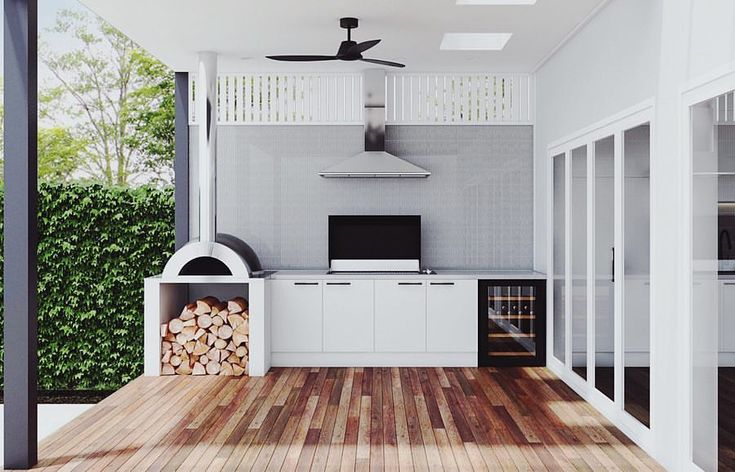 an outdoor kitchen with wood flooring and white cabinets on either side of the oven