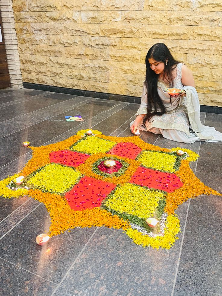 a woman sitting on the ground next to a flower arrangement