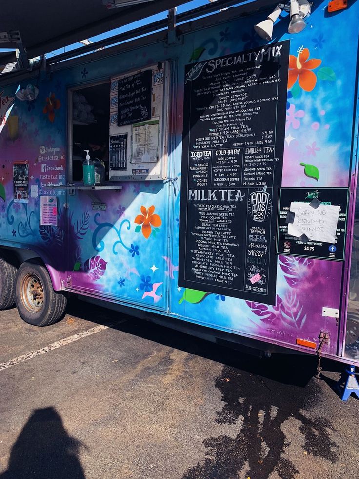 a colorful food truck parked in a parking lot next to another vehicle with menus on the side