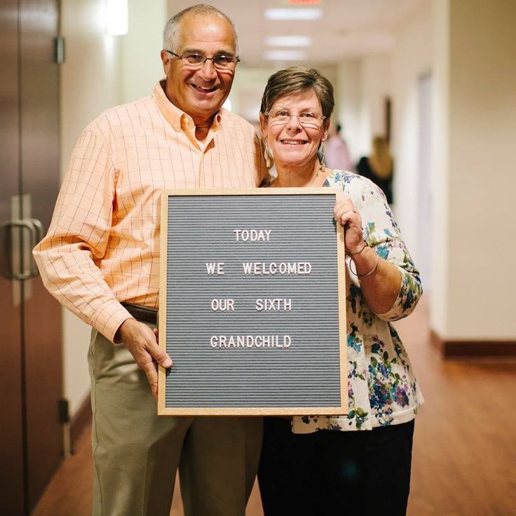 an older couple holding up a sign that says today we welcome our smith grandchild