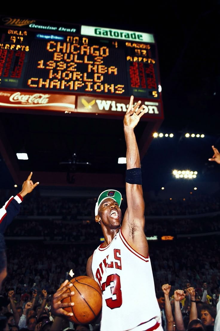 a man holding a basketball up in the air with his arm raised above his head