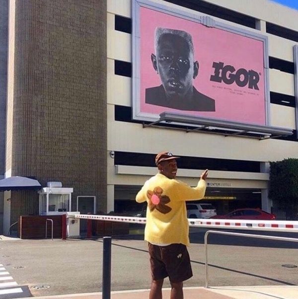 a man standing in front of a building with a giant billboard behind him that says icor