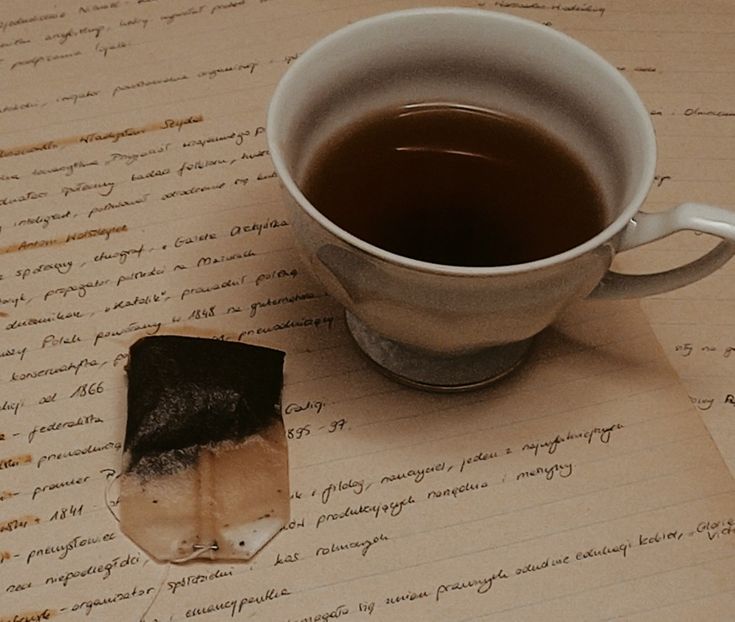 a cup of tea next to a piece of paper with writing on it