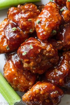 a white plate topped with chicken wings covered in bbq sauce and garnished with parsley