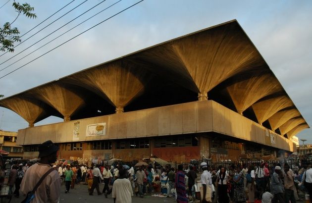 a large group of people standing outside of a building with an open roof on top