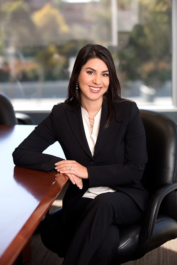 a woman sitting at a desk with her arms crossed in front of her chest, smiling for the camera