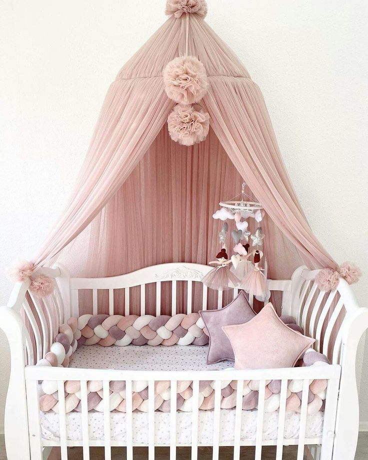 a baby crib with pink and white decor