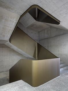 an artistic metal stair case in a concrete building with stairs leading up to the second floor