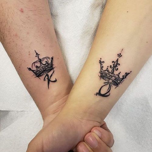 two people holding hands with tattoos on their arms and one has a crown tattooed on the wrist