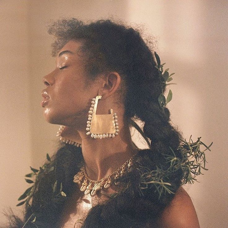 a woman with long hair wearing large earrings and necklaces on her neck, looking off to the side