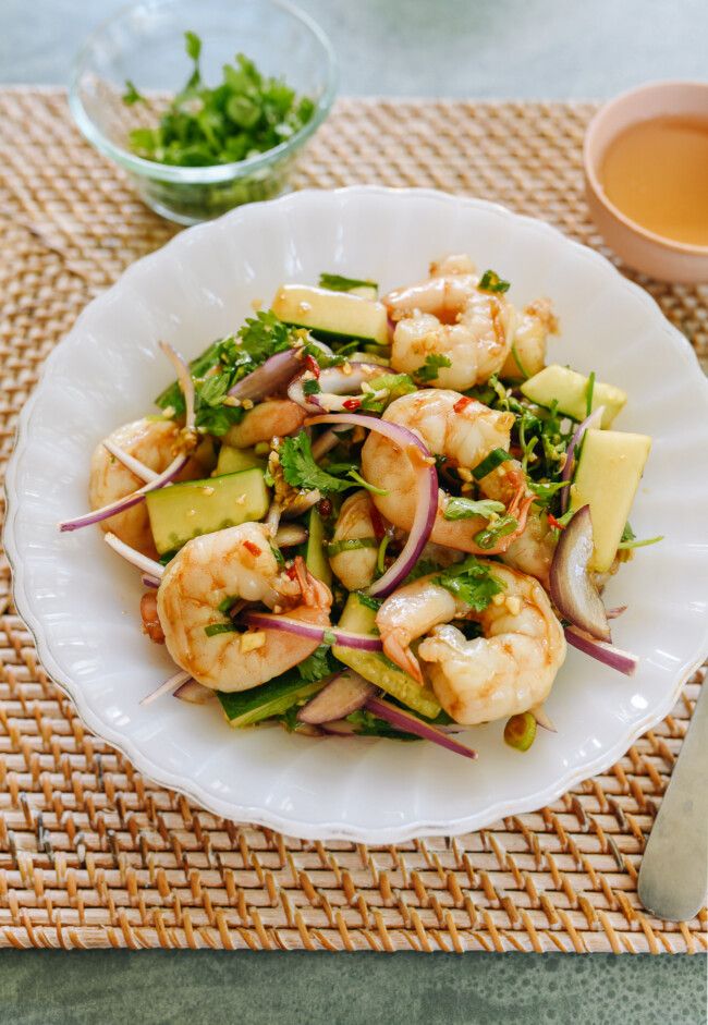 a white plate topped with shrimp and veggies next to a cup of tea