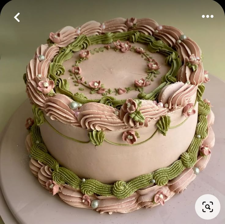 a decorated cake sitting on top of a white plate with pink and green frosting