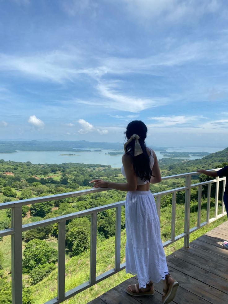 two people standing on a balcony looking at the ocean