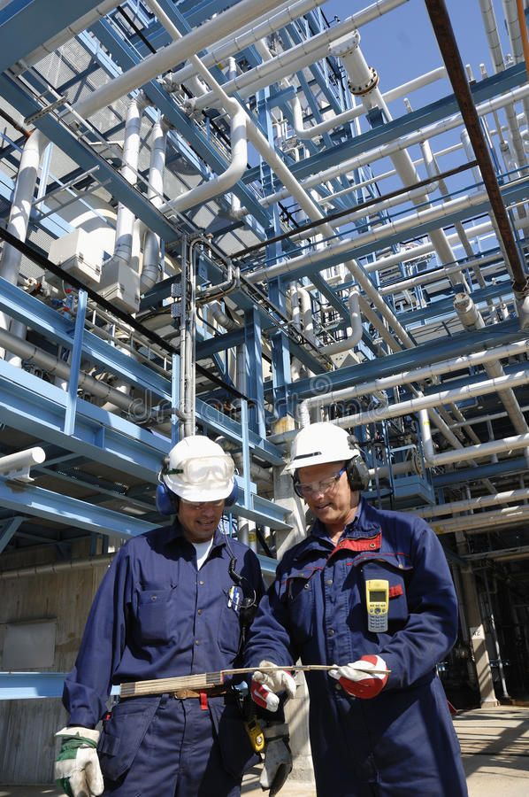 two men standing next to each other in front of pipes