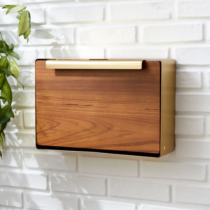 a wooden plaque mounted to the side of a white brick wall next to a potted plant