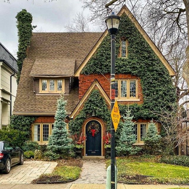 a house with ivy growing all over it's roof and windows, along with a car parked in front