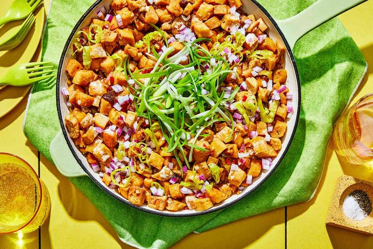 a large pan filled with food sitting on top of a green cloth next to utensils