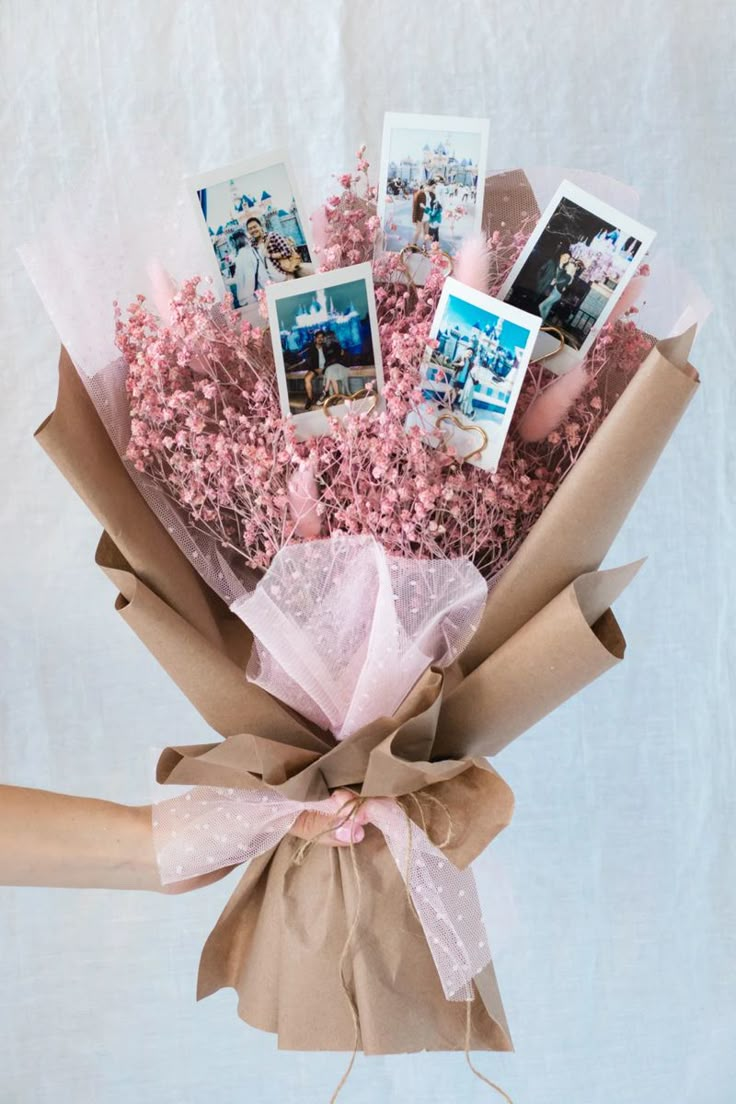 a bouquet of pink flowers with pictures on them in a brown paper wrap around it