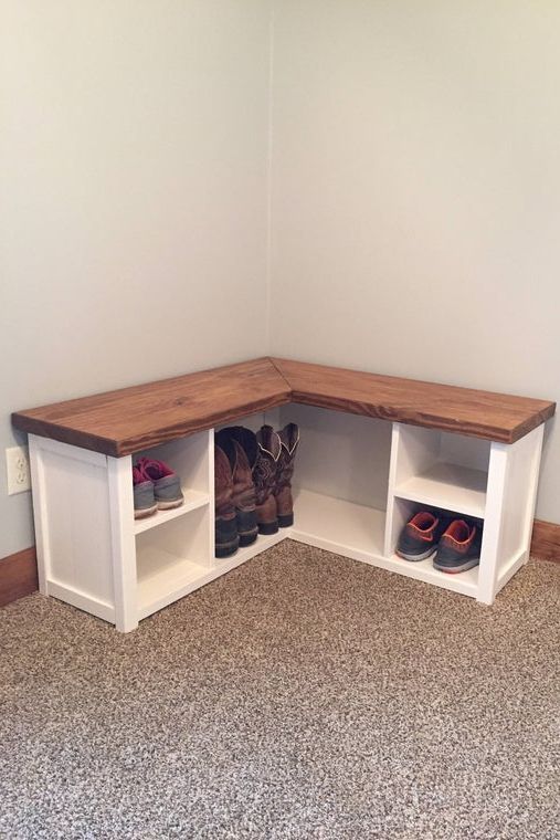 a corner bench with two cubbys and shoes on the bottom shelf in an empty room