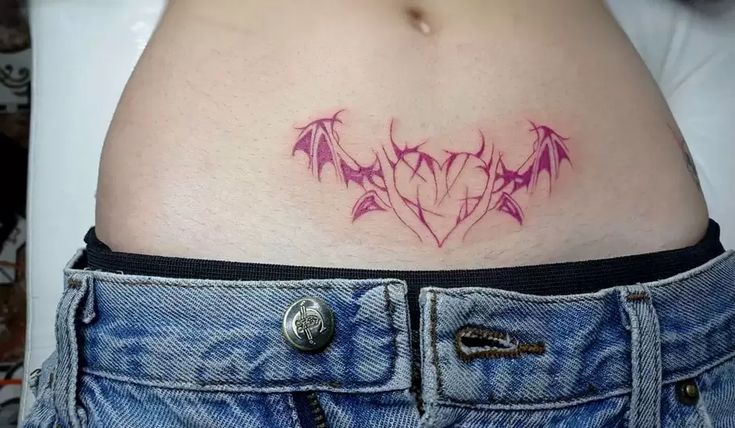 a woman's stomach with a tattoo on it that has pink flowers in the shape of a heart