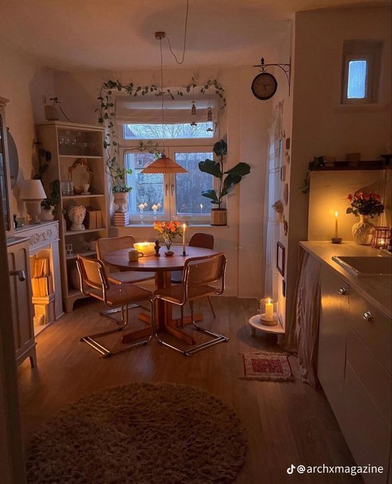 a dining room table and chairs in front of a window with candles on the windowsill