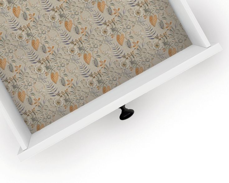 an empty white shelf with a floral wallpaper pattern on the bottom and black handles