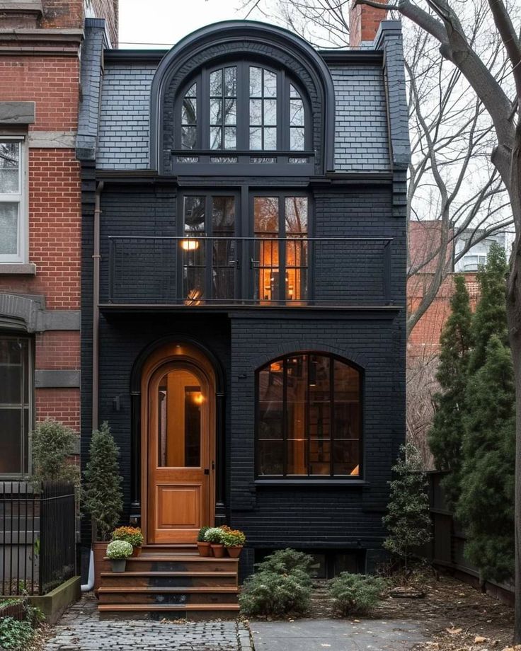 a black house with an arched window and wooden steps leading up to the front door