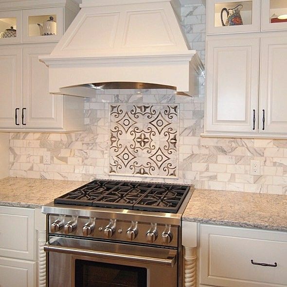 a stove top oven sitting inside of a kitchen next to white cabinets and counter tops