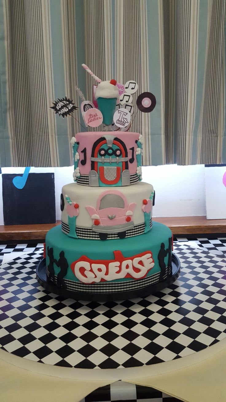 a three tiered cake on top of a black and white checkered table