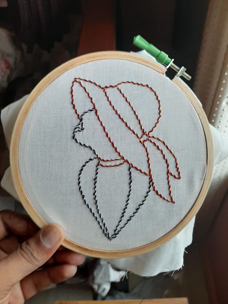 someone is holding up a small embroidery project