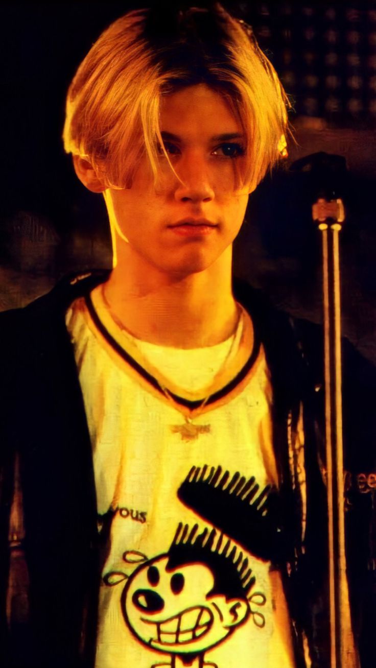 a young man with blonde hair holding a microphone