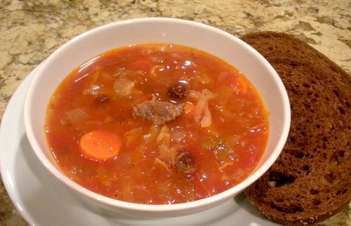 a bowl of soup next to a piece of bread