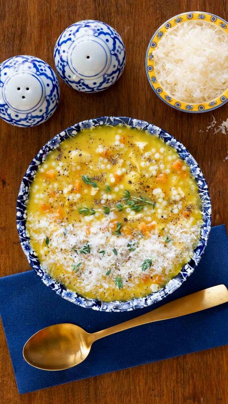 a bowl filled with soup next to two spoons on top of a wooden table