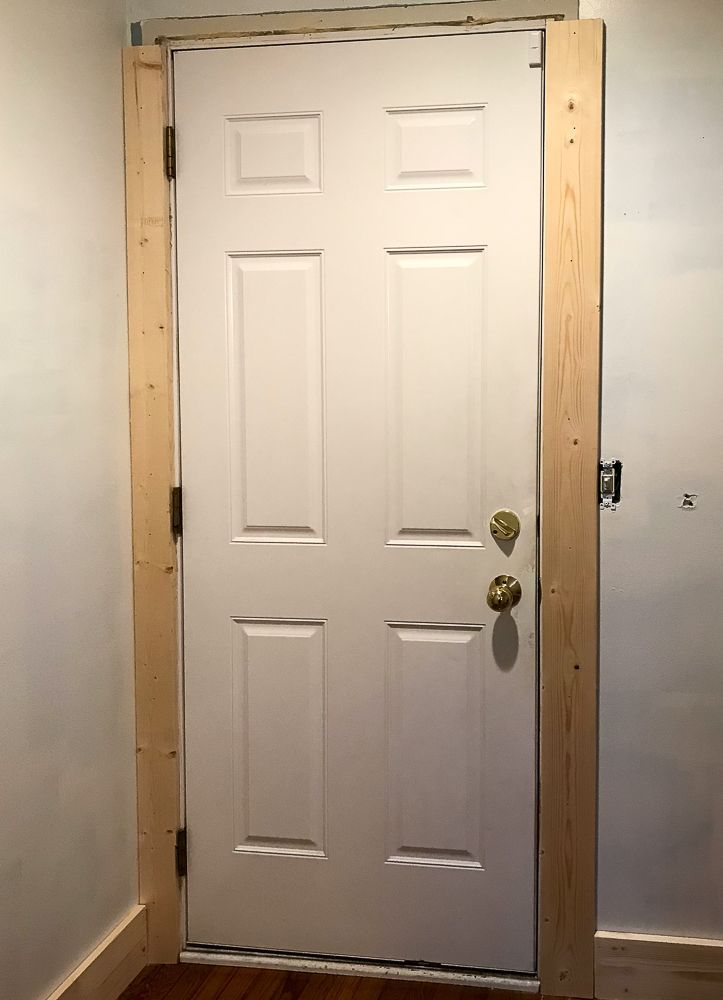 an empty room with a white door and wood flooring on the wooden frame around it