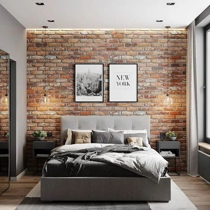 a bedroom with brick walls and flooring is pictured in this image, there are two framed pictures on the wall above the bed