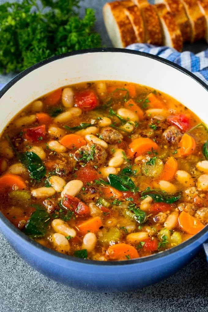 a blue bowl filled with soup next to bread and parsley on the side,