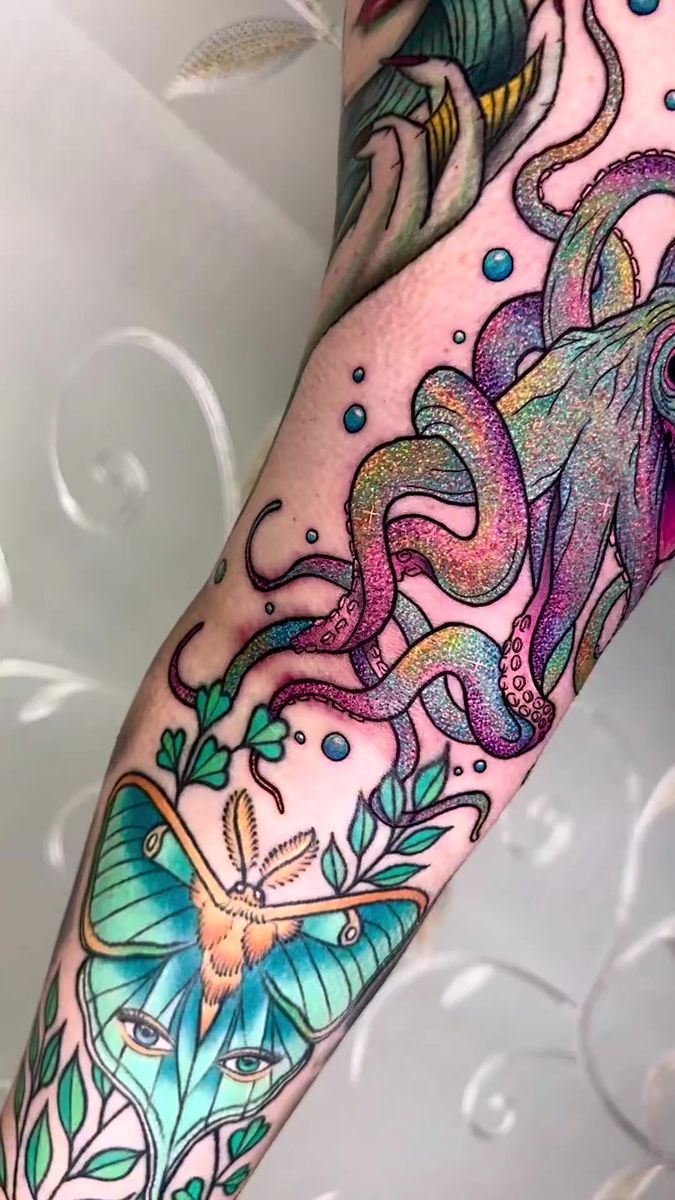 an arm with tattoos on it that has octopus and fish in the water around them